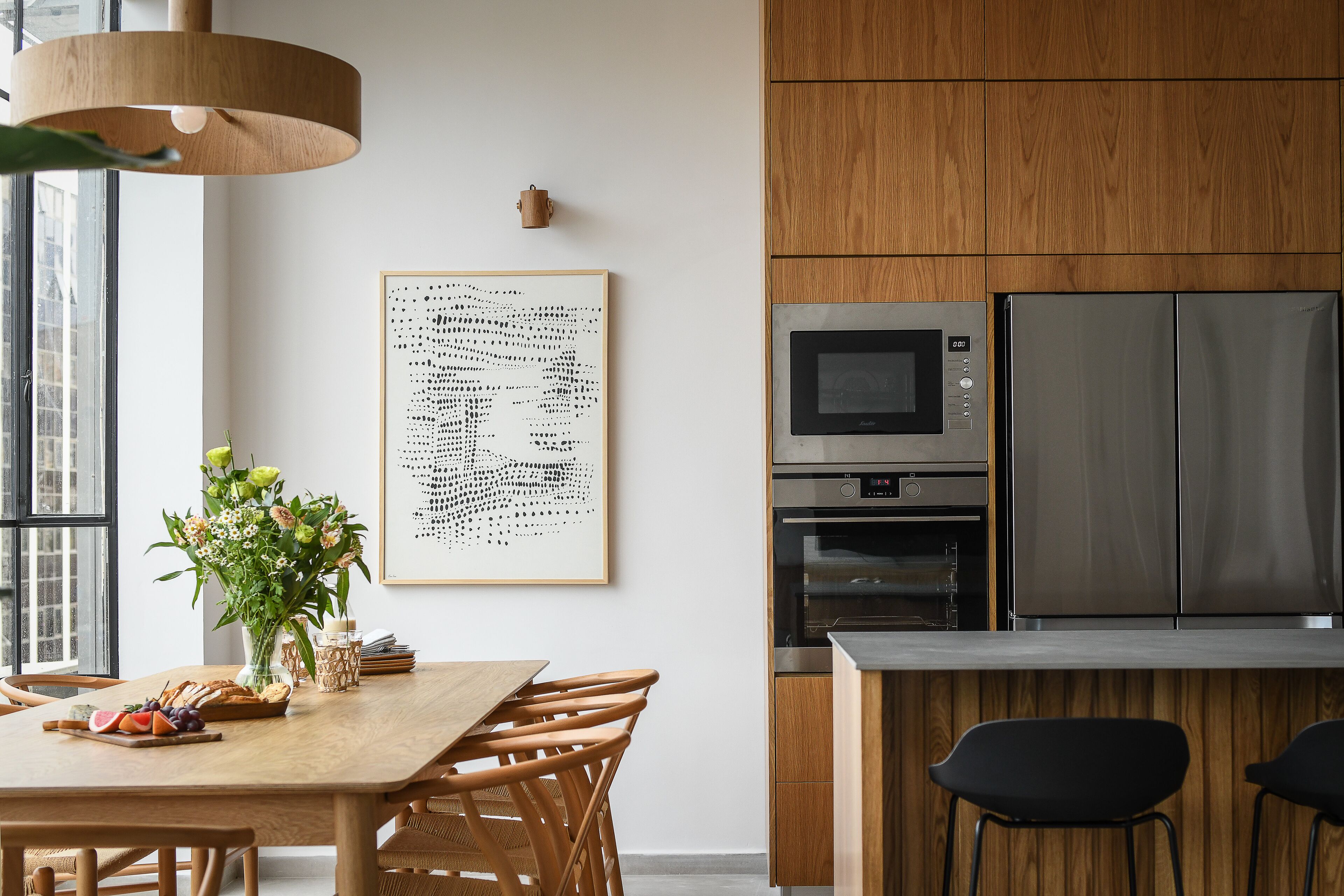 A modern kitchen with wooden cabinets, stainless steel appliances, and a dining area with a wooden table and chairs.