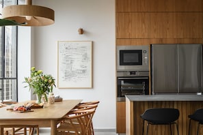 Una cocina moderna con armarios de madera, electrodomésticos de acero inoxidable y una zona de comedor con mesa y sillas de madera.