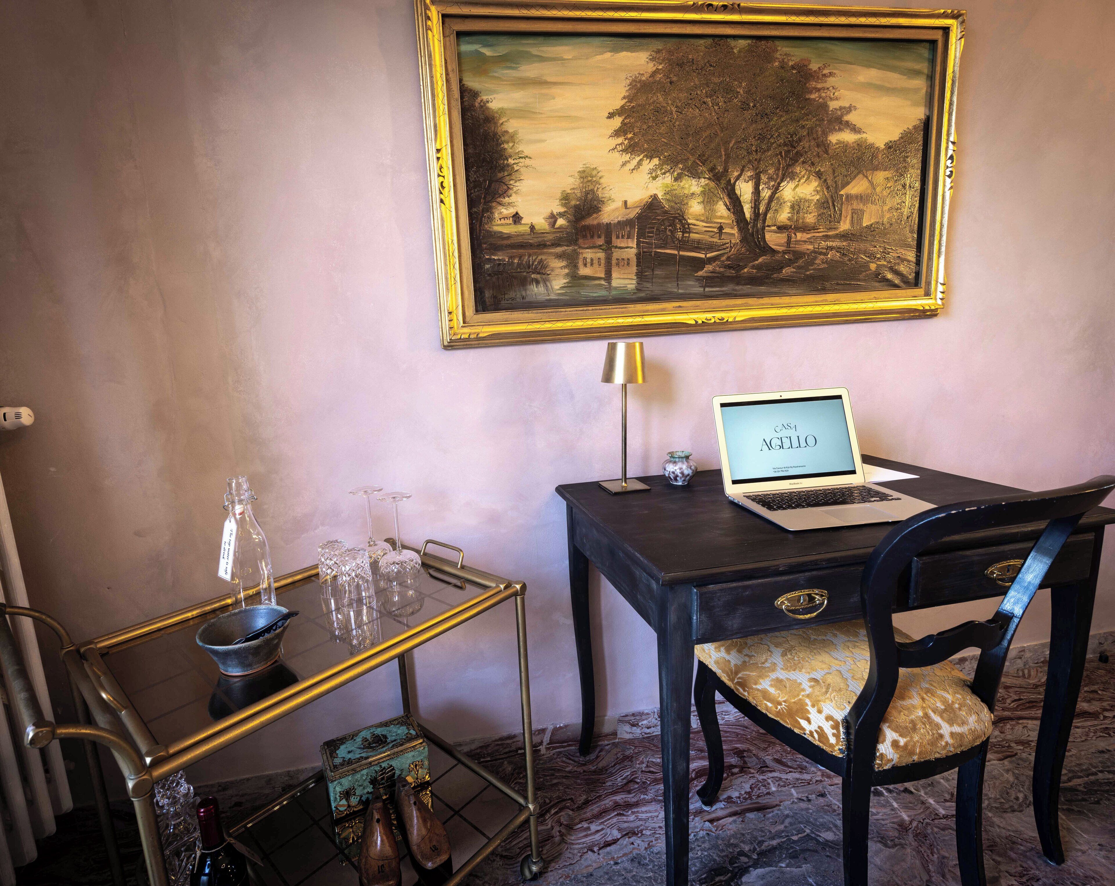 Una habitación con un escritorio, una computadora portátil y un cuadro en la pared.
