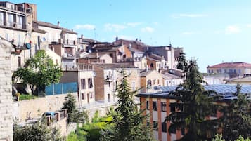 Vista de un pueblo histórico con edificios tradicionales, cielo despejado y una lejana vista al mar.