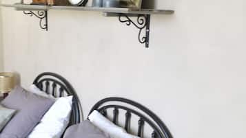 Un letto con testiera, cuscini, un comodino con lampada e una mensola con orologio e oggetti decorativi.