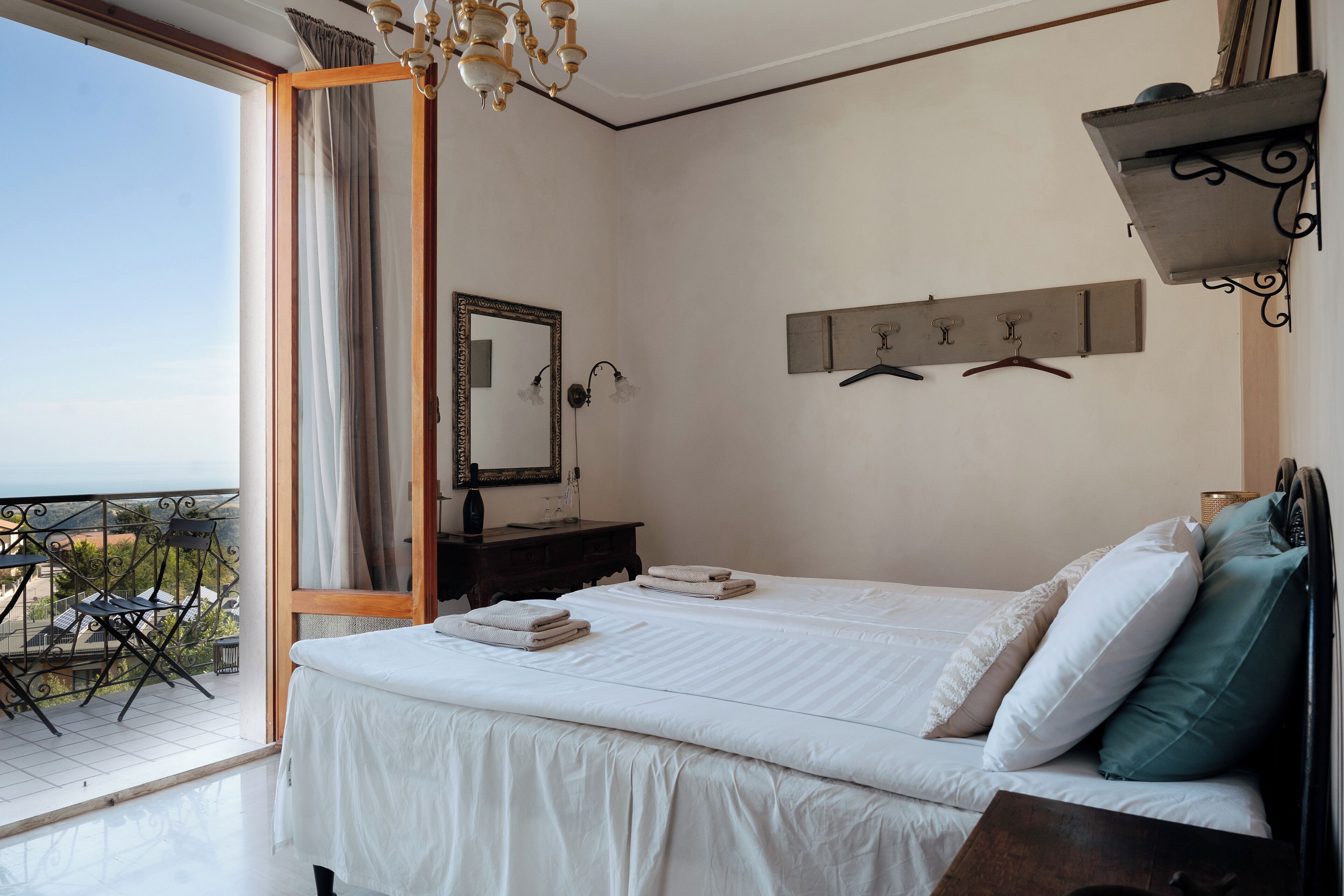Un dormitorio con una cama grande, un aparador, un espejo y vistas al exterior.