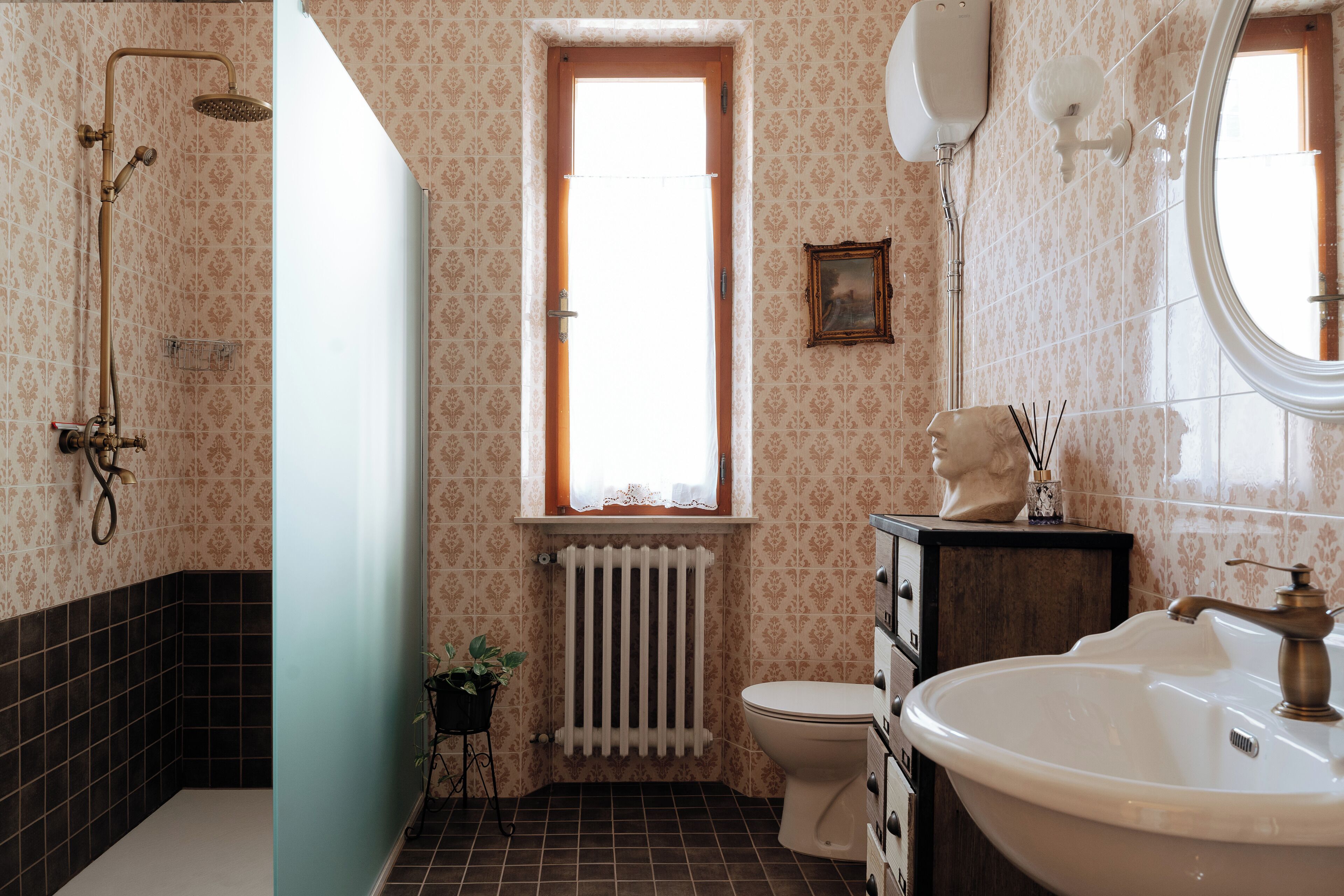 A bathroom with a shower, toilet, sink, and a radiator.