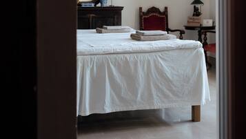 Un dormitorio con una cama, un tocador, un espejo, una silla roja y una araña.