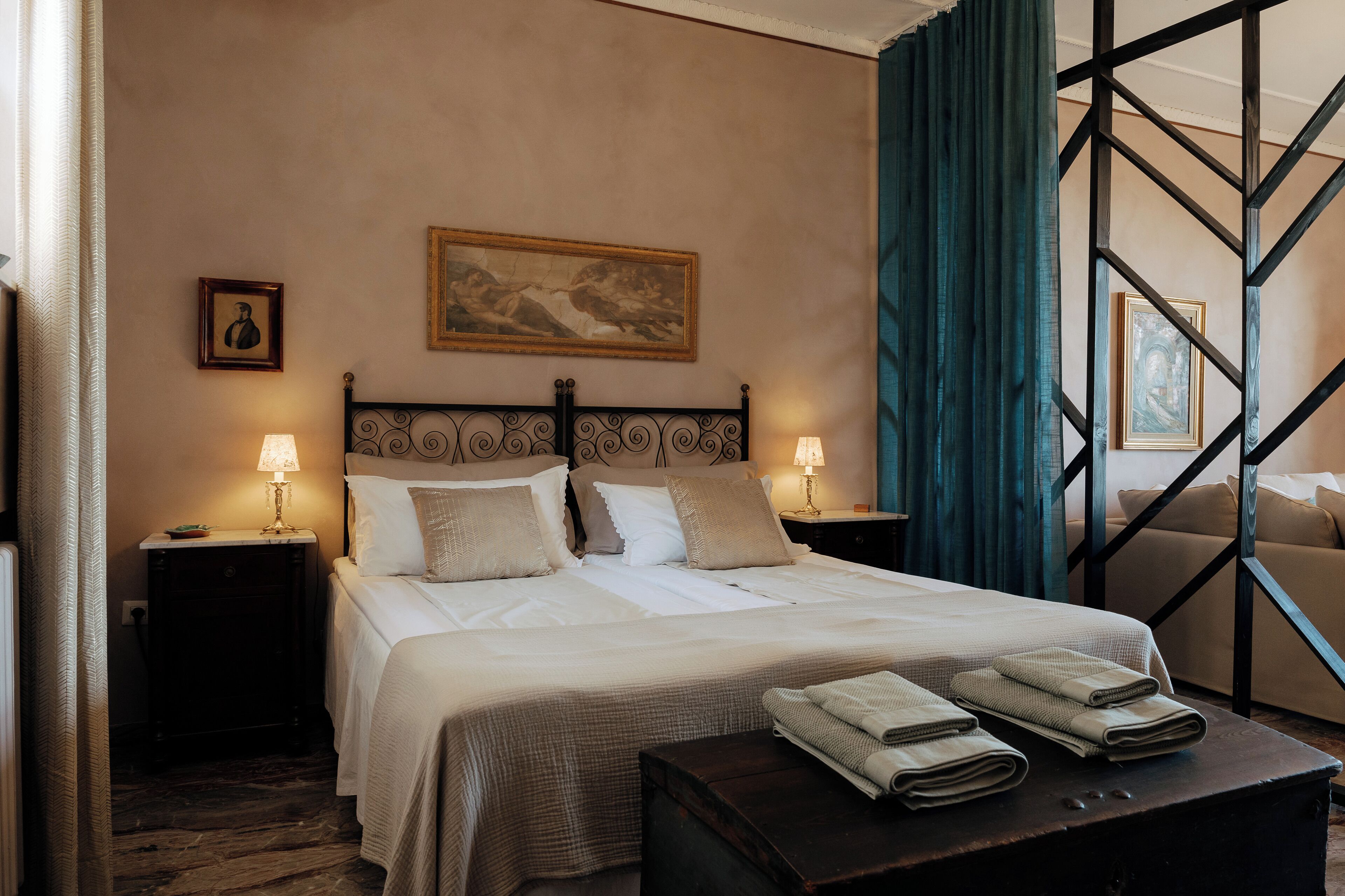 A neatly made bed with white linens, two bedside lamps, and a painting on the wall.
