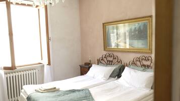 Ein Schlafzimmer mit einem Bett, einem Nachttisch, einem Fenster und einem Bild an der Wand.