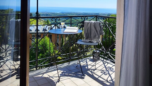 A balcony with a table, chair, and umbrella, overlooking a scenic view. - Casa Agello B&B (Ripatransone)