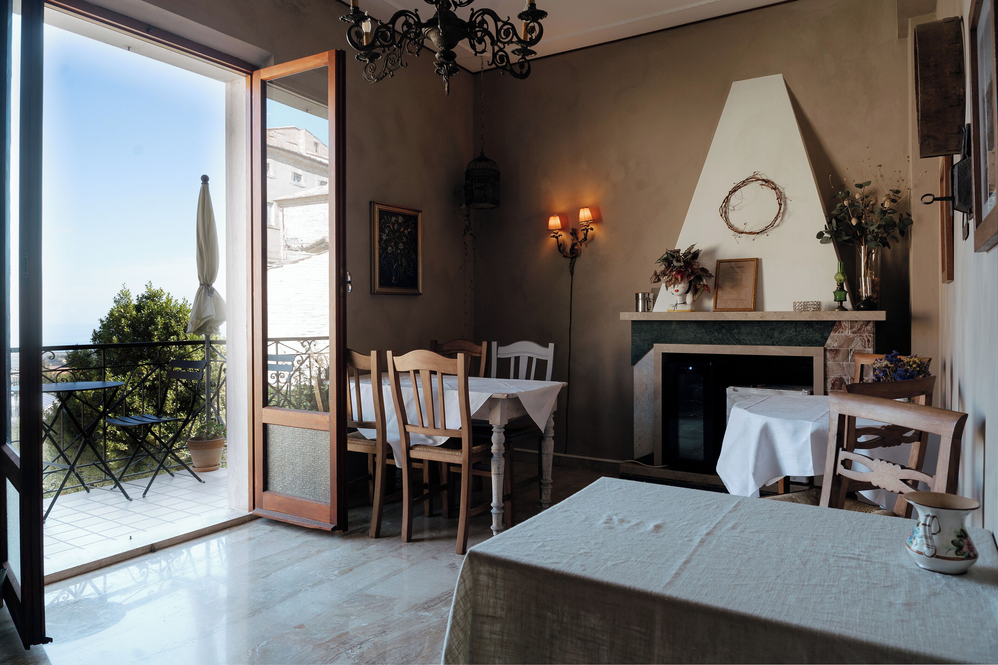 Comedor con mesa, sillas, una araña y vistas al balcón exterior.