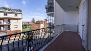 Ein Balkon mit Metallgeländer, der auf eine Straße und Häuser blickt.