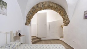 A bedroom with a bed, a nightstand, and a stone archway leading to a staircase. - Il Giardino by Interhome (Terzorio)