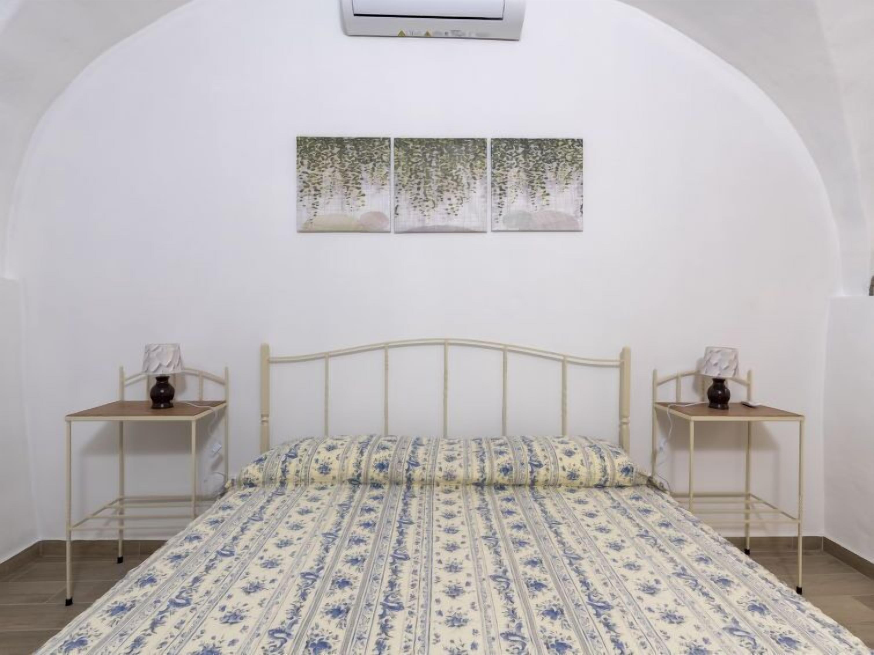 Une chambre à coucher avec un lit, deux tables de chevet et un climatiseur fixé au mur.