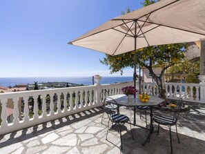 A stone-paved outdoor seating area with a table, chairs, and a large umbrella.
