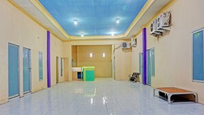 Un hall d’entrée spacieux et bien éclairé, doté de carreaux au sol, d’un comptoir d’accueil vert et de plusieurs portes.