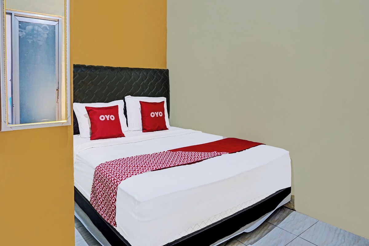 A hotel room with a bed, a headboard, and a window.