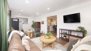 Un salon moderne avec un canapé, une table basse ronde et un téléviseur à écran plat fixé au mur.