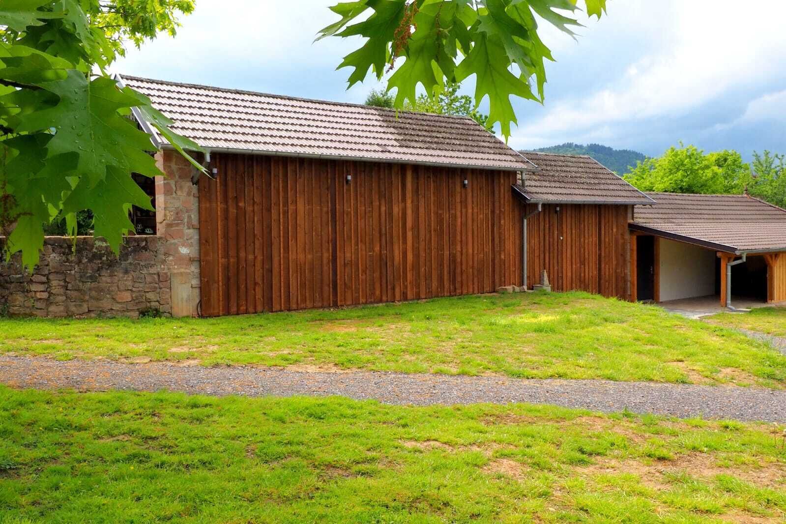 A rustic barn with a stone wall and a covered porch.