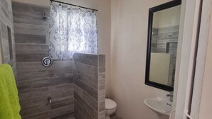 Een badkamer met douche, toilet en wastafel.