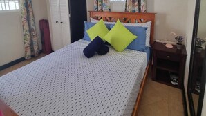 Een slaapkamer met een bed, nachtkastje, kledingkast en een raam met gordijnen.