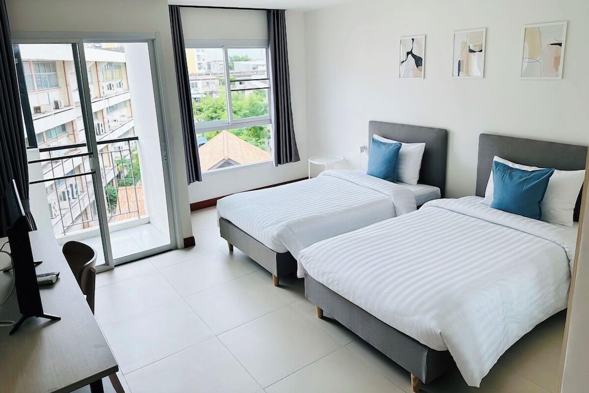 Une chambre d’hôtel avec deux lits, un bureau et une vue sur la ville.