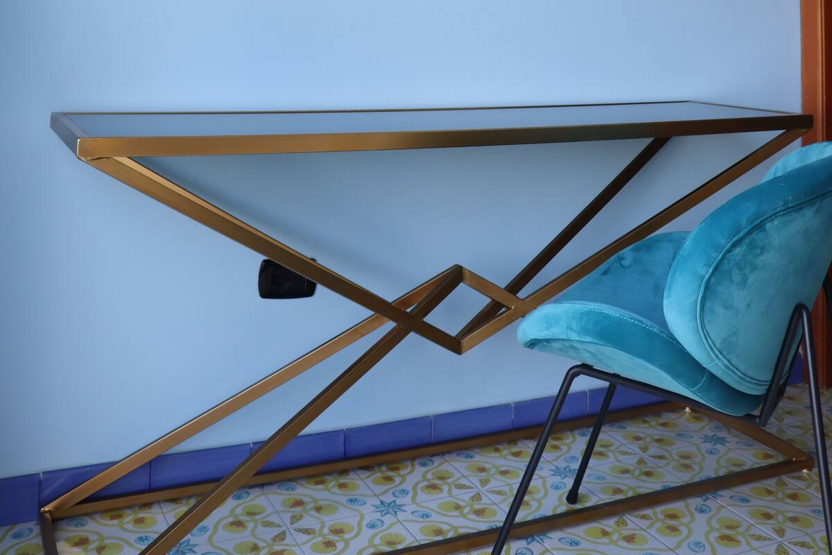 A room with a large abstract blue painting on the wall, a modern chair, and a geometric metal table.