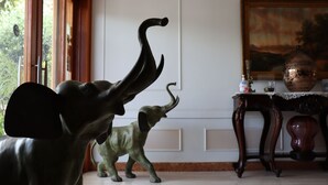 Ein Zimmer mit einer großen Elefantenskulptur, einem Holztisch mit einer Vase und einem Bild an der Wand.