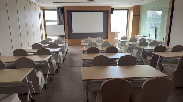 A classroom with rows of desks and chairs, a projector screen, and a large window. - UrCove by Hyatt Shanghai Wujiaochang (Shanghai)