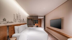 A modern hotel room with a large bed, a flat-screen TV, and a cityscape mural on the wall.