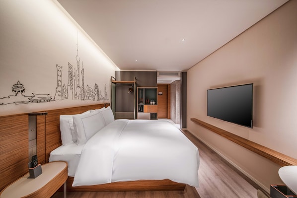 Et moderne hotelværelse med en stor seng, et fladskærms-tv og et bybillede malet på væggen.