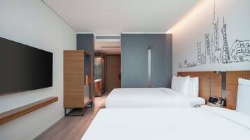 Une chambre d’hôtel moderne dotée d’une grande télévision à écran plat, de deux lits, d’une armoire et d’un mur orné d’une fresque représentant un paysage urbain.
