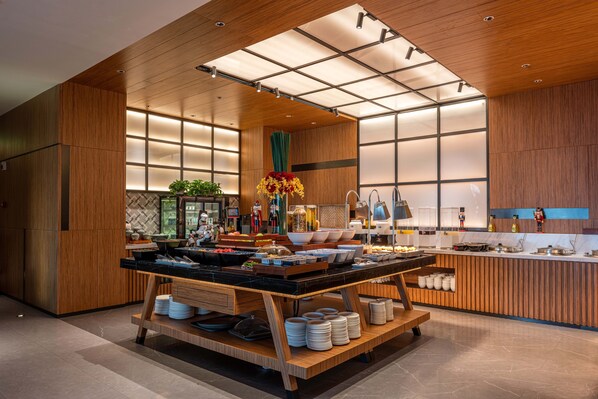 A modern kitchen with wooden accents, a central island with dishes, and a view of the adjacent dining area. - UrCove by Hyatt Shanghai Wujiaochang (Shanghai)