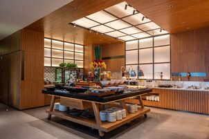 Cocina moderna con detalles de madera, una isla central con vajilla y vistas al área de comedor contigua.