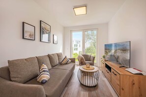 A living room with a sofa, a coffee table, a TV, and framed artwork on the wall. - Hochwertiges Ferienappartement für bis zu 4 Personen in Ruhiger Wohngegend an de (Zirchow)