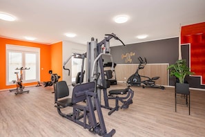 Un gimnasio con equipo de ejercicio, un ventanal grande y una frase motivacional en la pared.