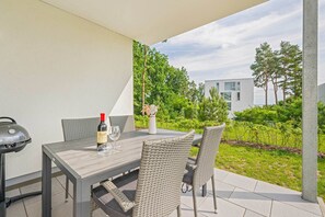 An outdoor patio with a table, chairs, a wine bottle, and a grill. - Hochwertiges Ferienappartement für bis zu 4 Personen in Ruhiger Wohngegend an de (Zirchow)