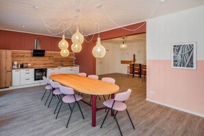 A modern kitchen with a wooden countertop, white cabinets, and a dining area with a wooden table and pink chairs. - Hochwertiges Ferienappartement für bis zu 4 Personen in Ruhiger Wohngegend an de (Zirchow)