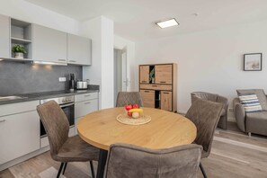 Una cocina moderna con una mesa de comedor redonda, sillas tapizadas en gris y un armario de madera.