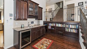 A kitchen with dark wooden cabinets, a stainless steel oven, and a red rug.