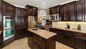 A modern kitchen with dark wood cabinets, stainless steel appliances, and a granite countertop.
