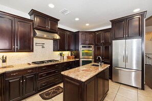 A modern kitchen with dark wood cabinets, stainless steel appliances, and a granite countertop.