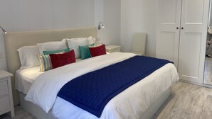 Et soveværelse med en seng, to natborde, en garderobe og en sengetavle.