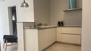 Et moderne køkken med en indbygget ø, rustfrie hårde hvidevarer og en hængende lampe.