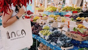 En bod med et udvalg af frugt og grøntsager, herunder druer, bananer og røde peberfrugter.
