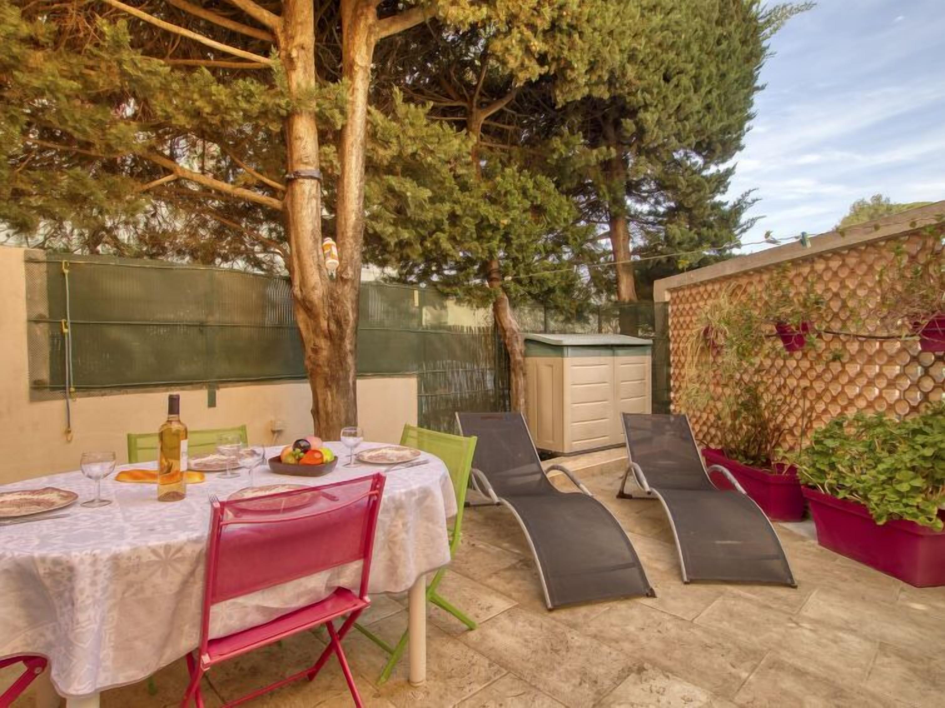 An outdoor patio with a table set for dining, surrounded by chairs and a pergola.