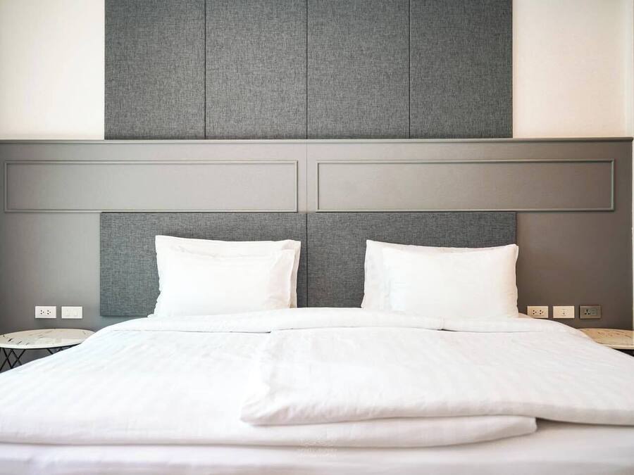 A hotel room with a large bed, two bedside tables, and a grey headboard.