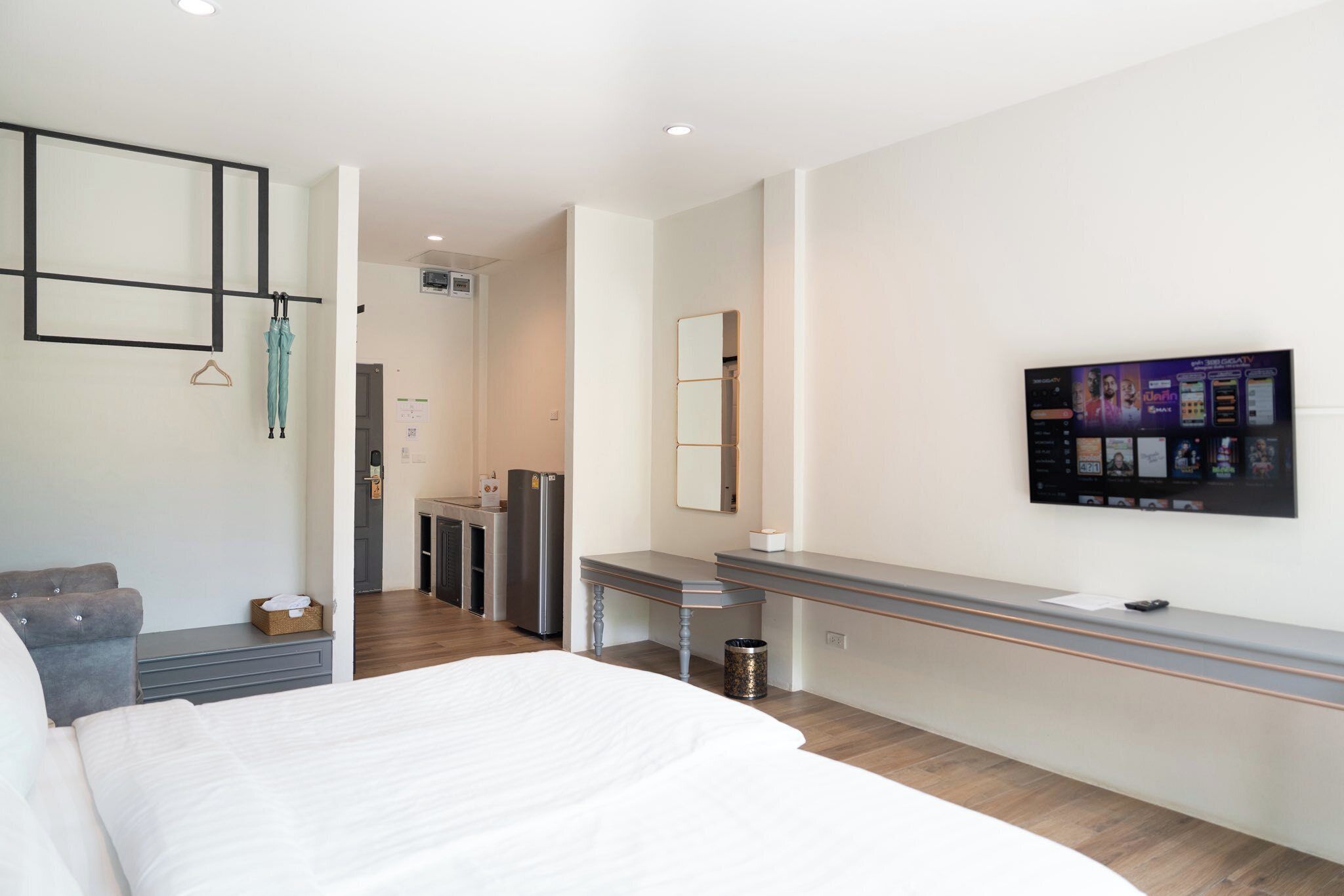 Una habitación de hotel moderna con una cama grande, un escritorio, un espejo y un televisor montado en la pared.