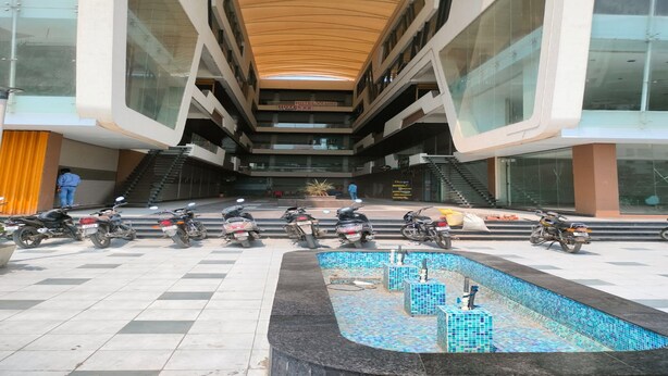 A modern building with a central atrium, multiple floors, and a tiled floor. - Hotel R R One (Vadodara)