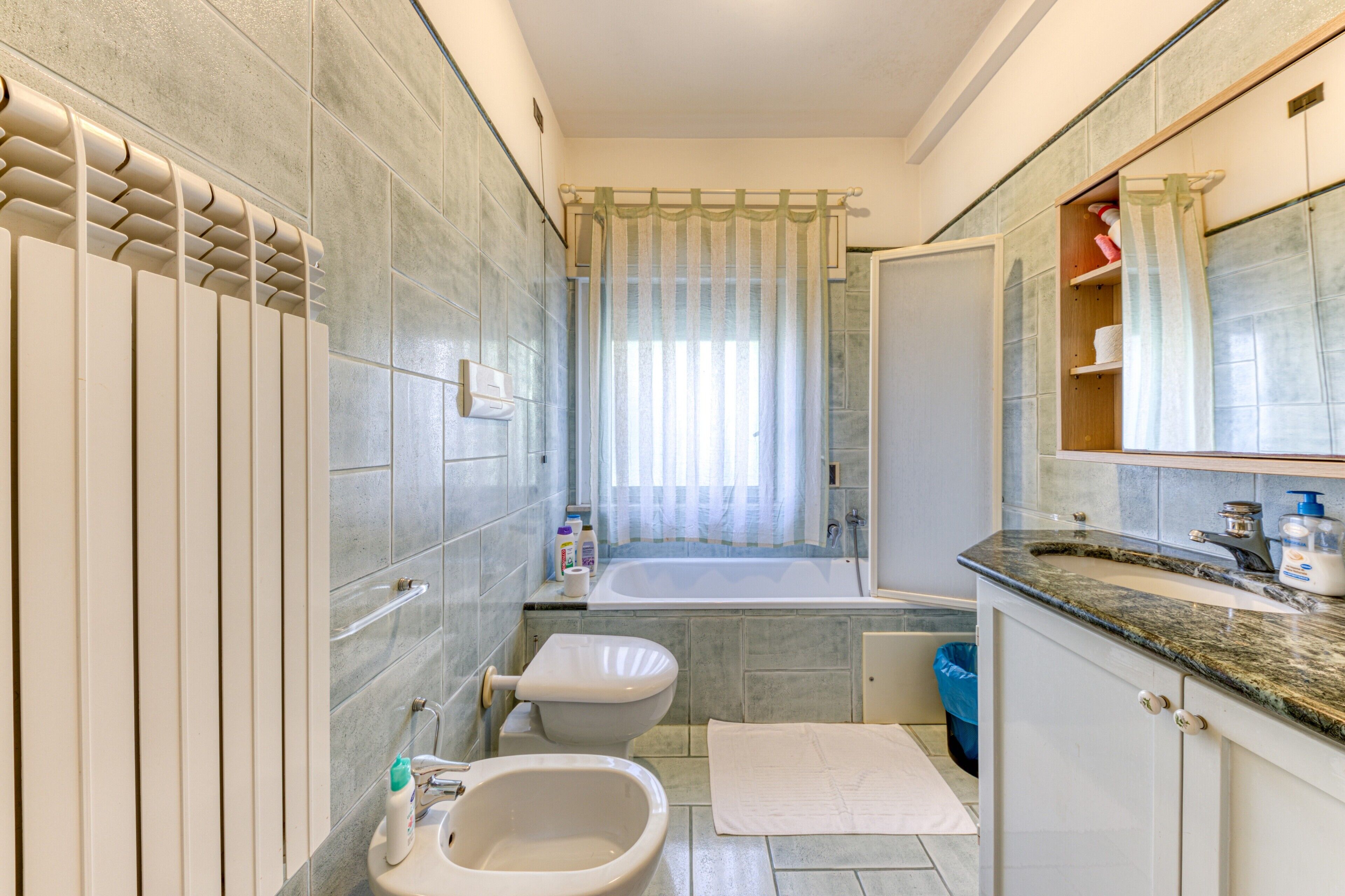 Ein modernes Badezimmer mit Badewanne, Toilette, Bidet und einem Waschtisch mit Spiegel.