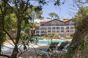 A hotel with a pool, surrounded by trees and a clear sky. - Studio "Olivia" with Shared Pool, Private Terrace, and Wi-Fi (Moliets-et-Maa)