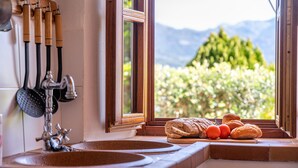 Una cocina con vistas a montañas, un lavamanos y diversos utensilios.