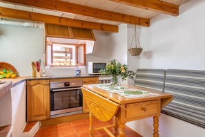 Une cuisine avec des meubles de rangement en bois, une cuisinière, un four à micro-ondes et une table avec un set de table.